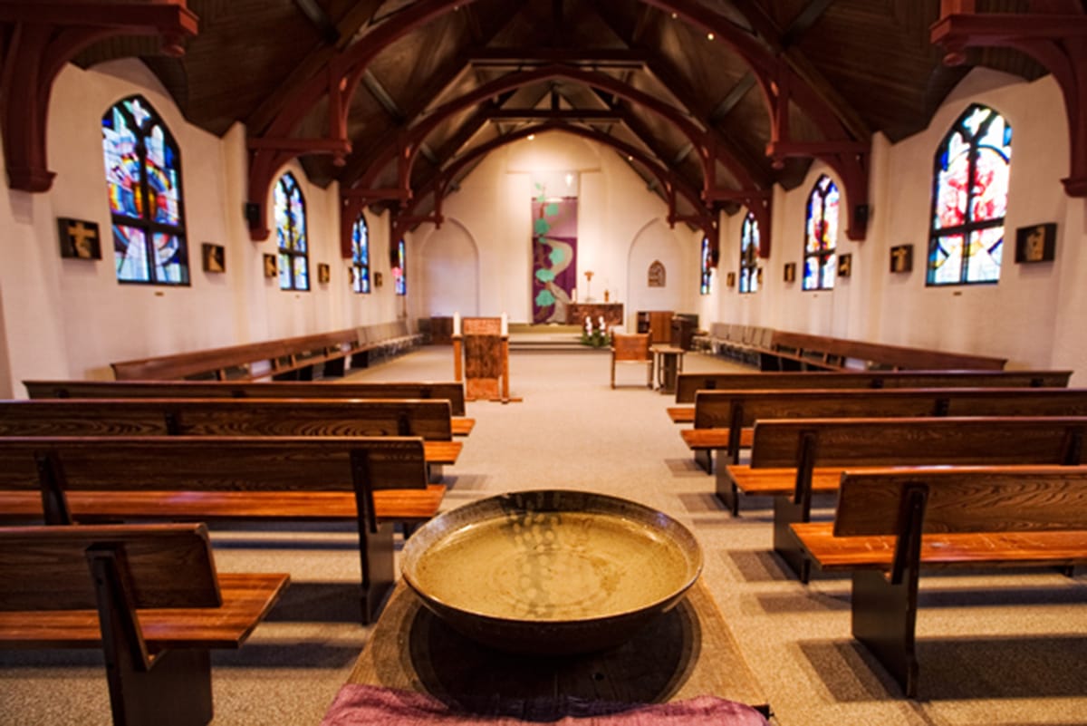 St. Jospeh's College Chapel, looking from the back towards the front you can see pews and stained glass windows.